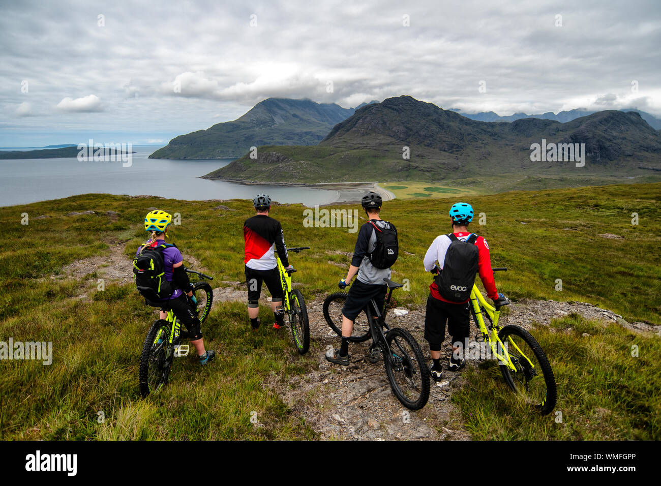 Quattro i ciclisti di montagna di guardare al di sopra della Baia Camasunary sull'Isola di Skye sulla costa ovest della Scozia. Foto Stock