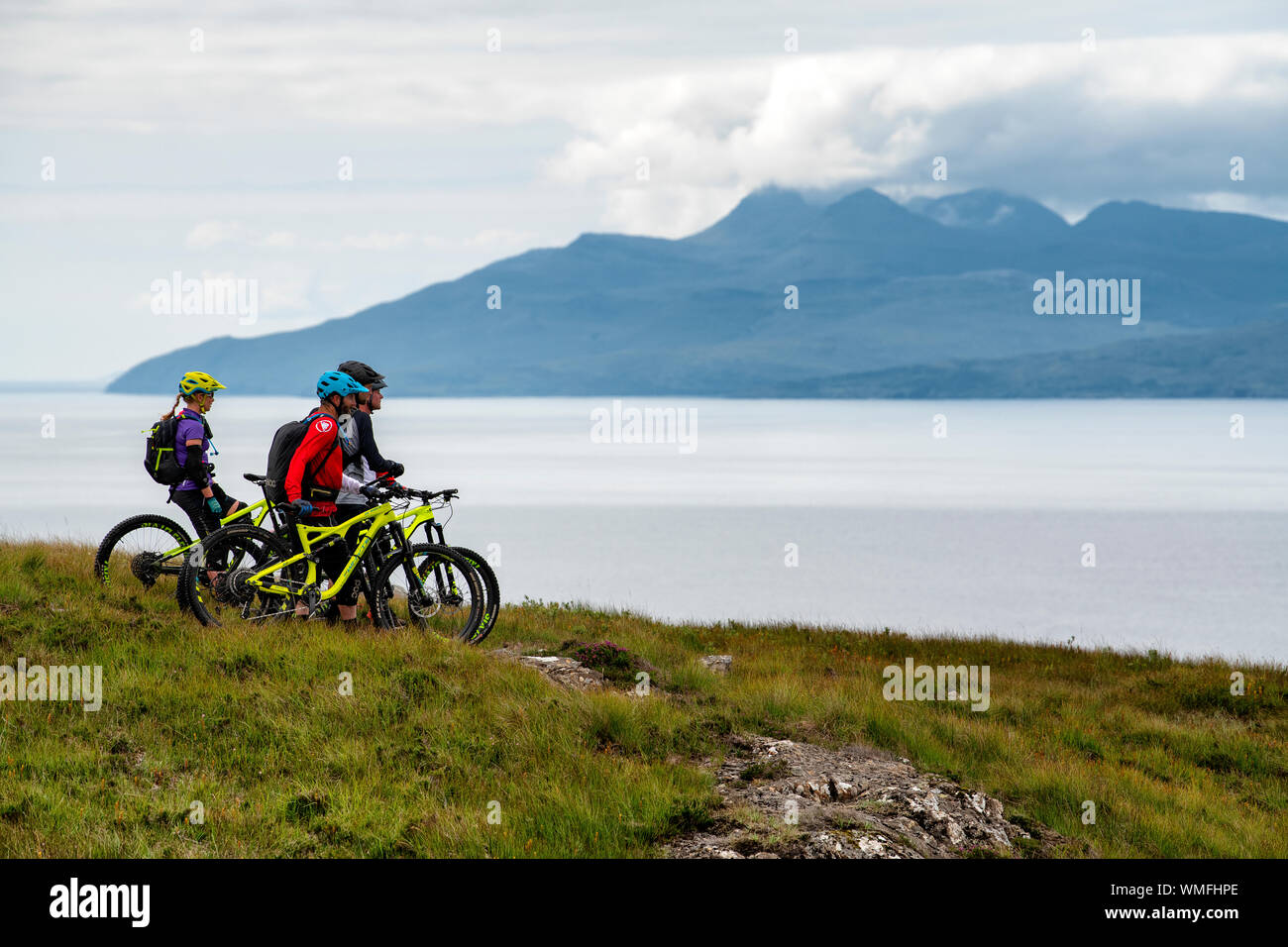 Quattro i ciclisti di montagna di guardare al di sopra della Baia Camasunary sull'Isola di Skye sulla costa ovest della Scozia. Foto Stock