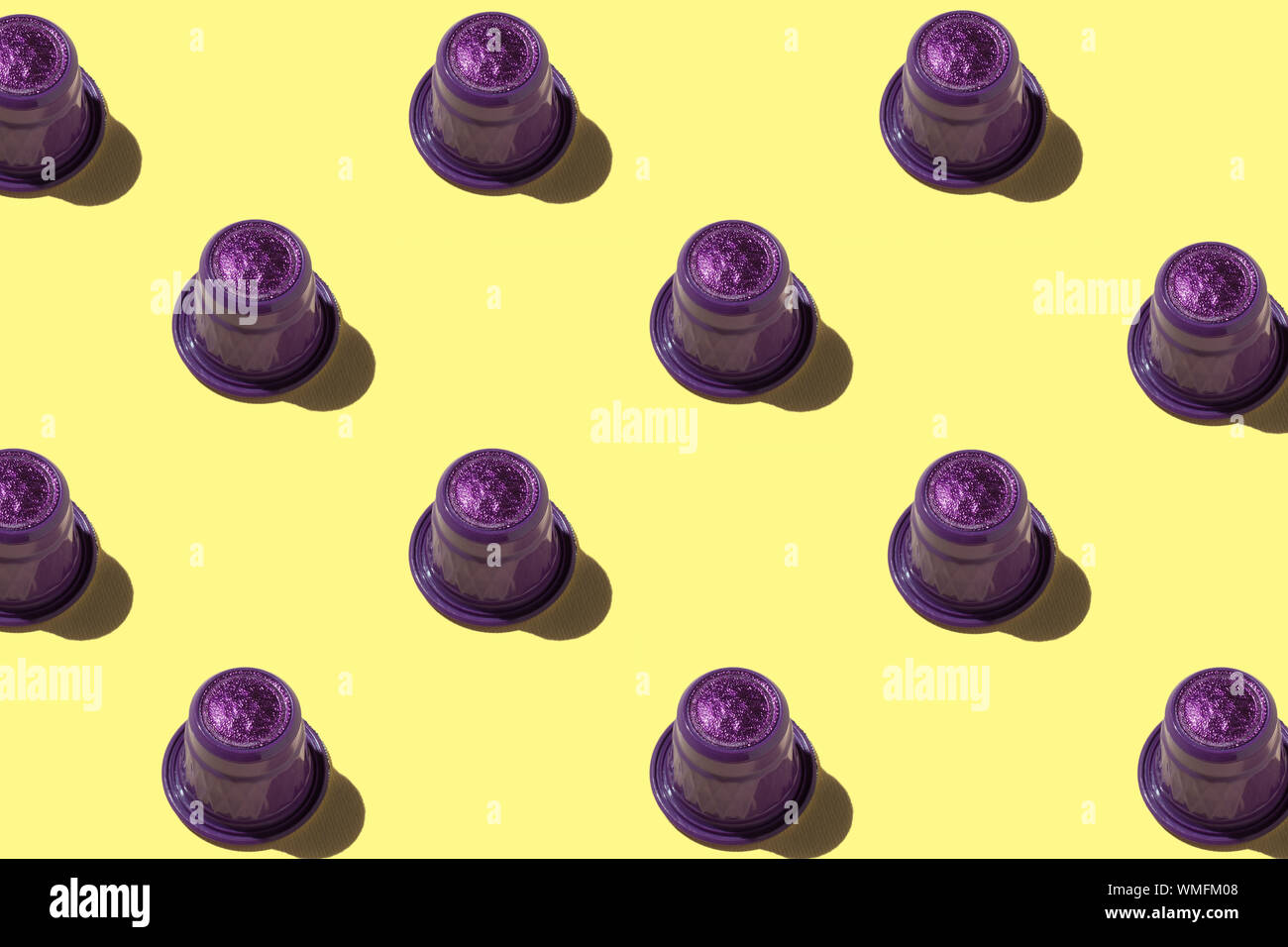 Colorato porpora e giallo modello di caffè espresso capsule su sfondo color pastello, vista dall'alto Foto Stock