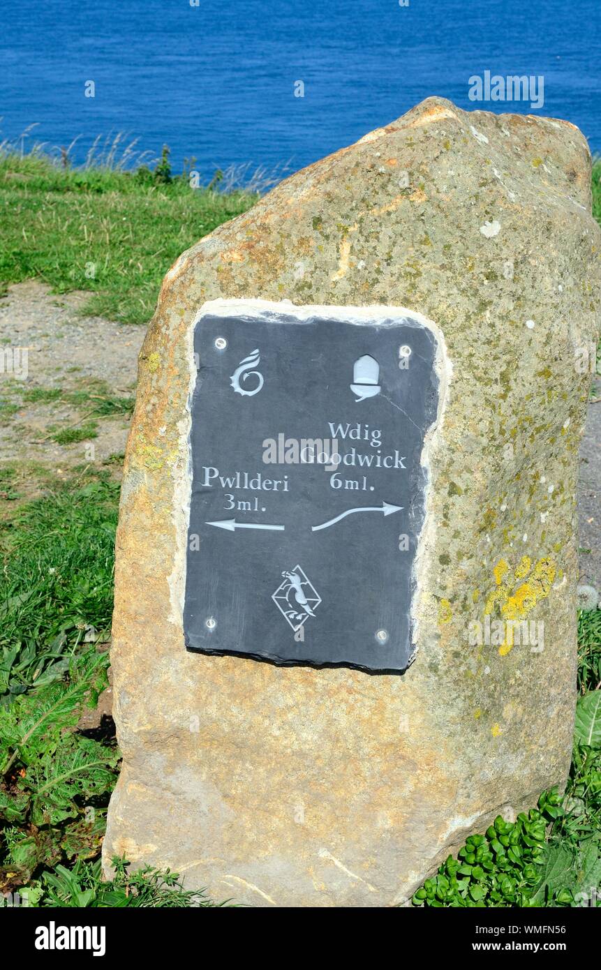 Segno di ardesia su una pietra di post che mostra le direzioni di Goodwick Pwllderi e Il Pembrokeshire Coast National Park Galles Cymru REGNO UNITO Foto Stock