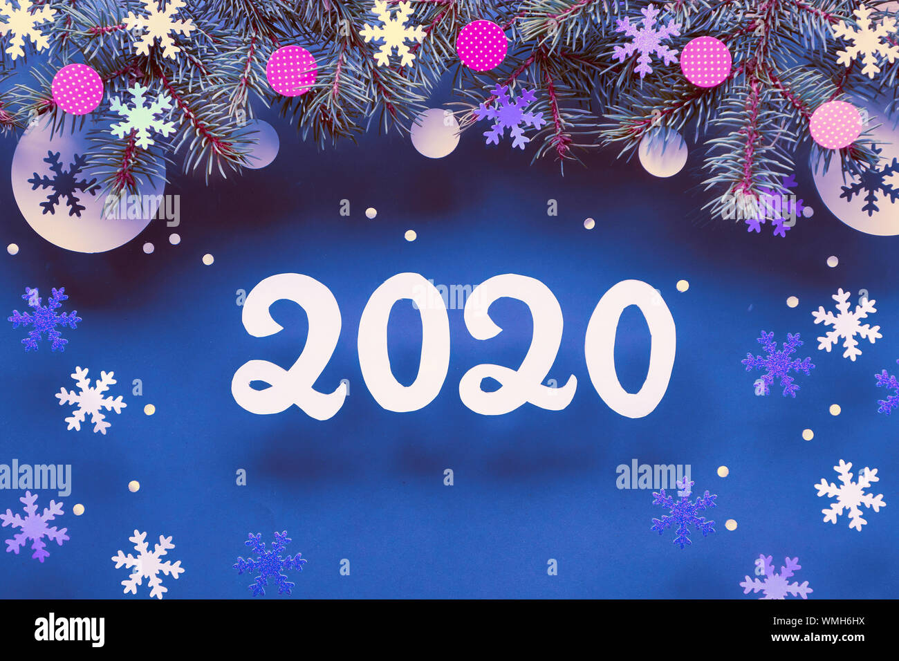 Felice Anno Nuovo 2020! Festosa sfondo inverno con ramoscelli di abete, viola, neon e white paper decorazioni. Appartamento laico, vista dall'alto sul blu scuro backgro carta Foto Stock