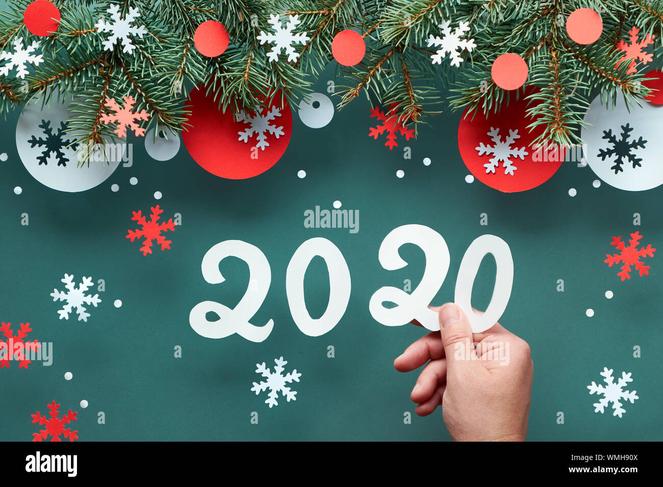 Mano azienda numero 2020, Natale sfondo con ramoscelli di abete rosso e bianco decorazioni di carta. Appartamento laico, vista dall'alto sul verde scuro lo sfondo della carta. Foto Stock
