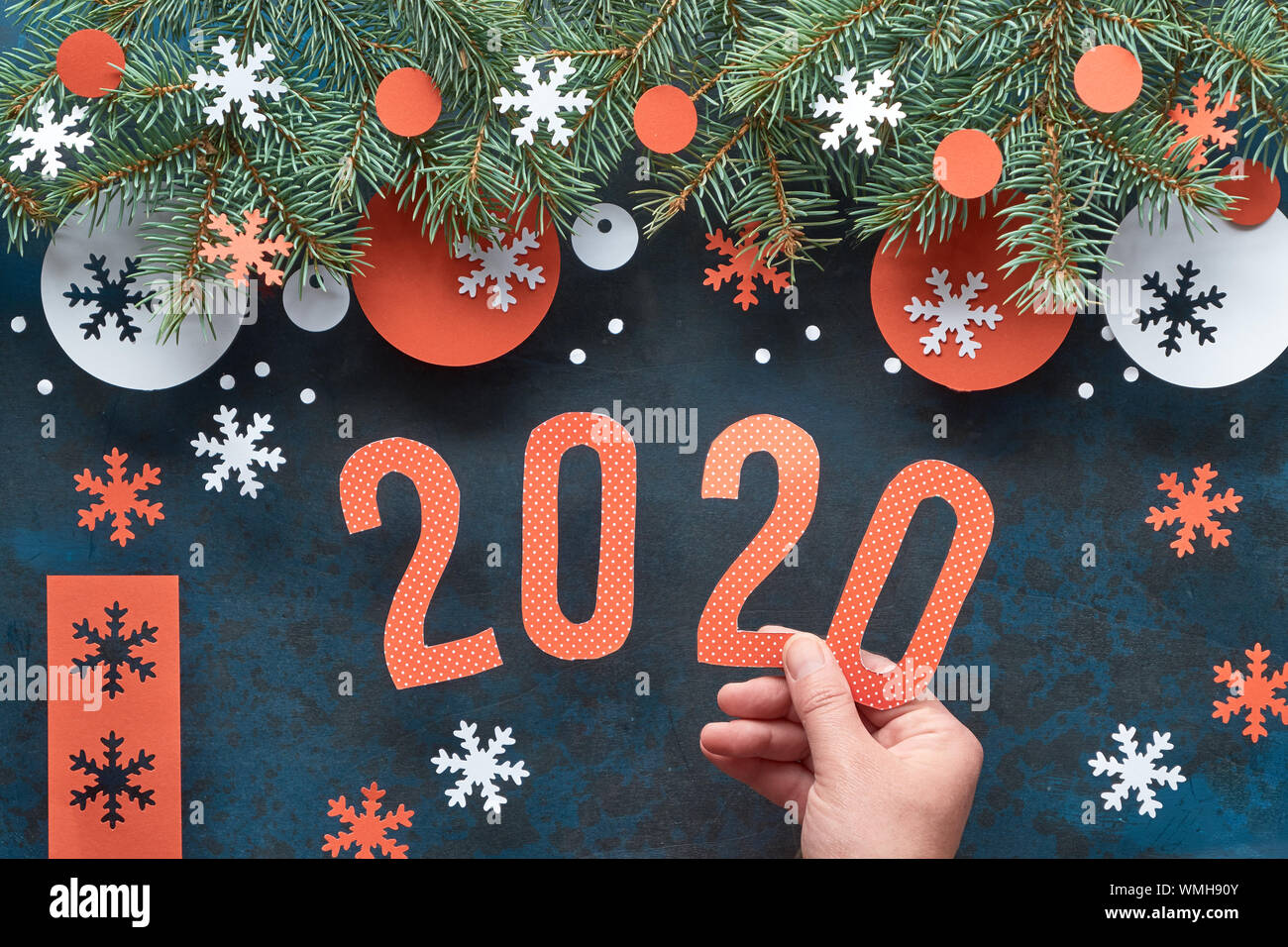Mano azienda numero 2020, Natale sfondo con ramoscelli di abete rosso e bianco decorazioni di carta. Appartamento laico, vista dall'alto sulla astratta scuro dello sfondo. Foto Stock