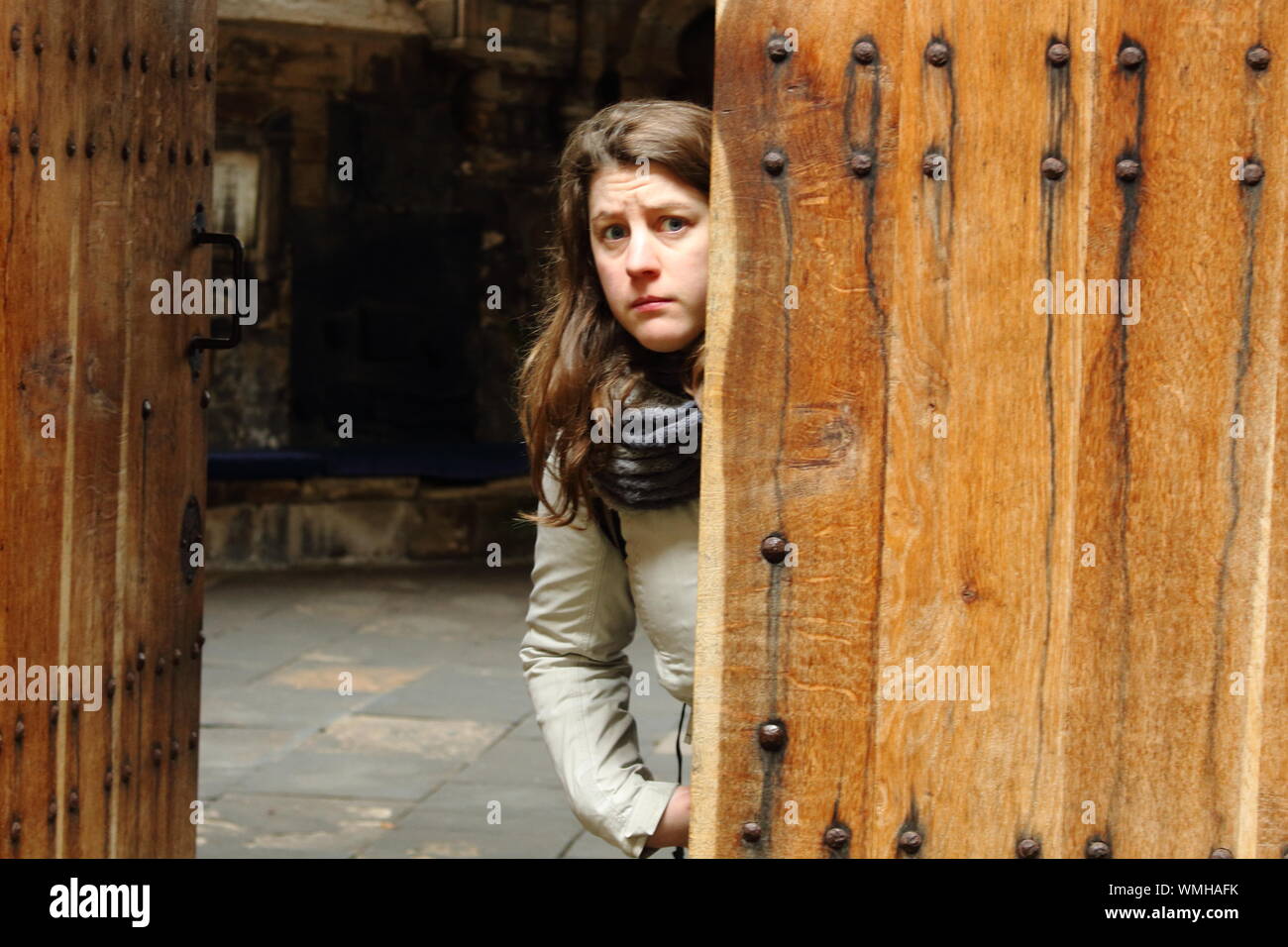 Ritratto di paura donna in piedi dalla porta di legno Foto Stock