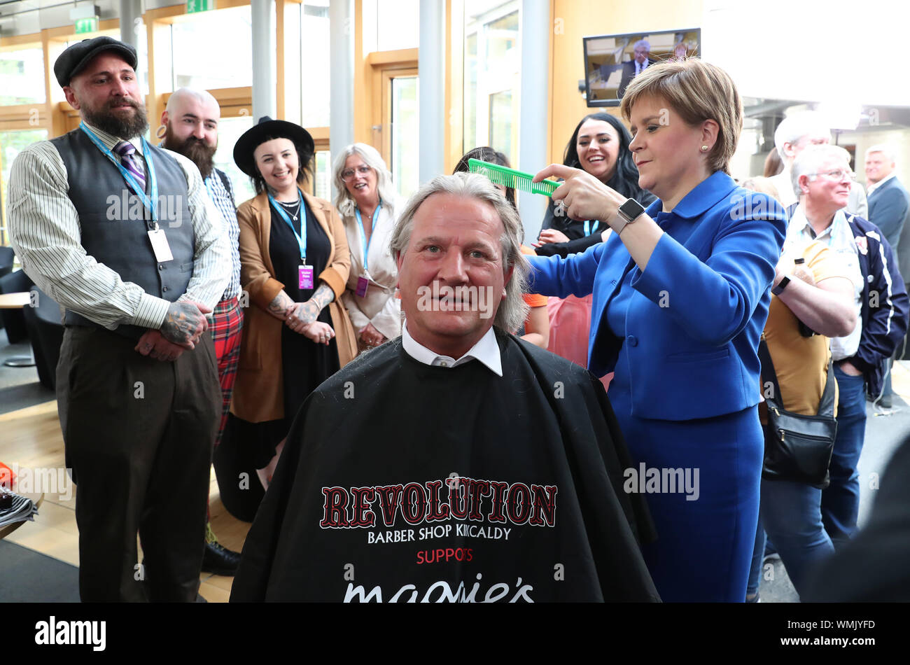 Primo Ministro Nicola Storione taglia i capelli di David Torrance MSP sollevamento £1000 per la carità Maggie's Centre in Kirkcaldy presso il parlamento scozzese di Edimburgo. Foto Stock