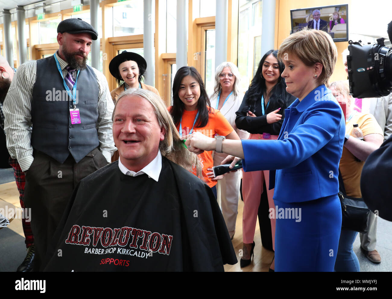 Primo Ministro Nicola Storione taglia i capelli di David Torrance MSP sollevamento £1000 per la carità Maggie's Centre in Kirkcaldy presso il parlamento scozzese di Edimburgo. Foto Stock