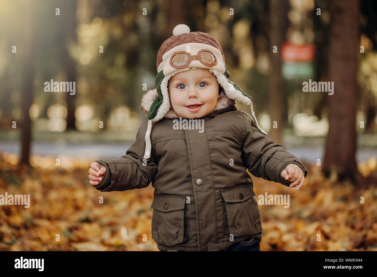 Little Boy nel cappuccio pilota giocando con Toy piano nel parco. L'autunno. Concetto sognare e viaggi Foto Stock