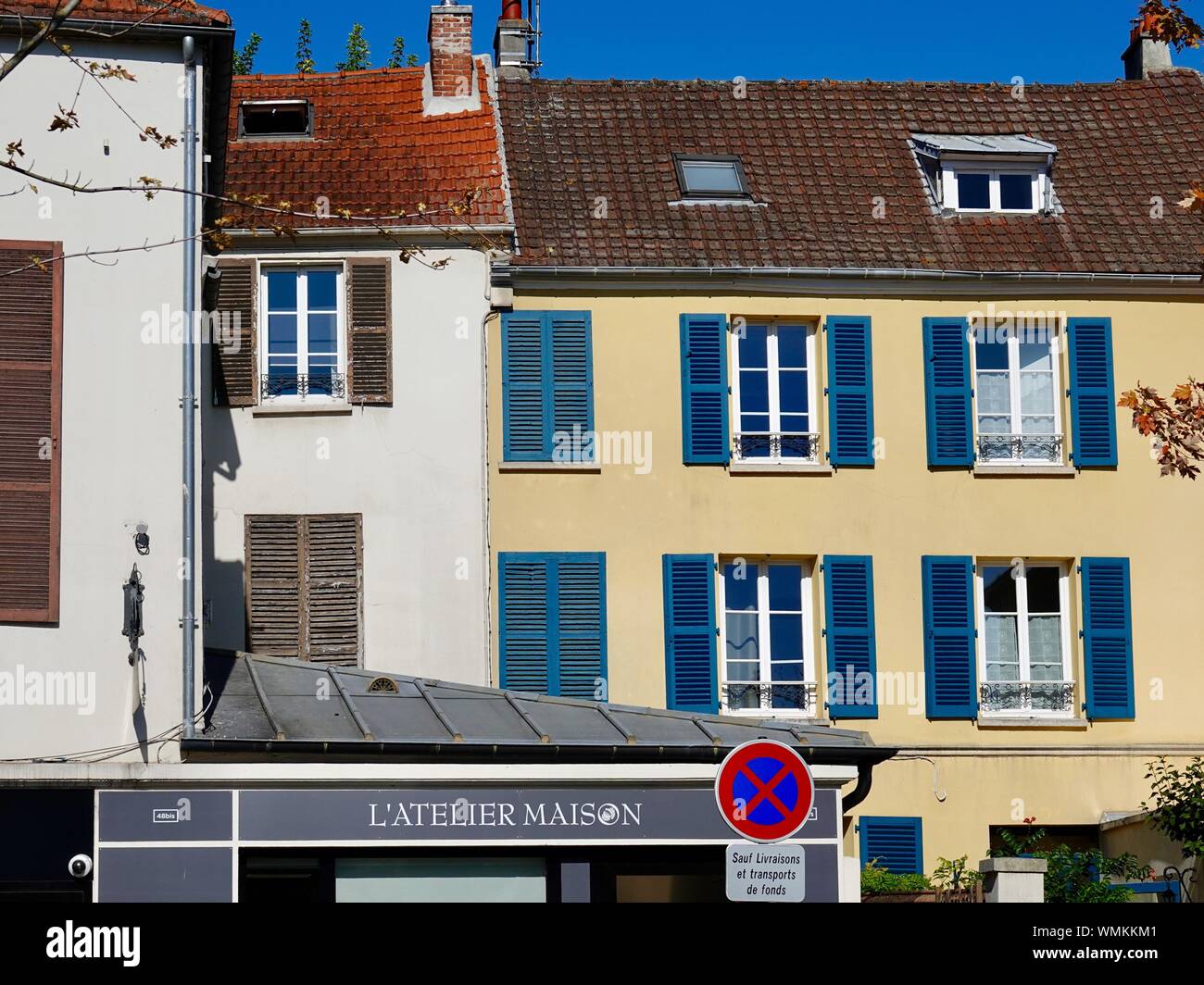 La porzione superiore di negozi, gialli e bianchi edifici, piccola cittadina nei pressi di Parigi, Main Street, Andrésy, Francia. Foto Stock