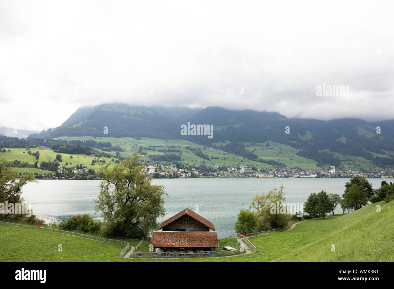 Una casa sul Lago Sarnen nel cantone di Obvaldo in Svizzera, con la città di Sachseln visibile attraverso il lago. Foto Stock