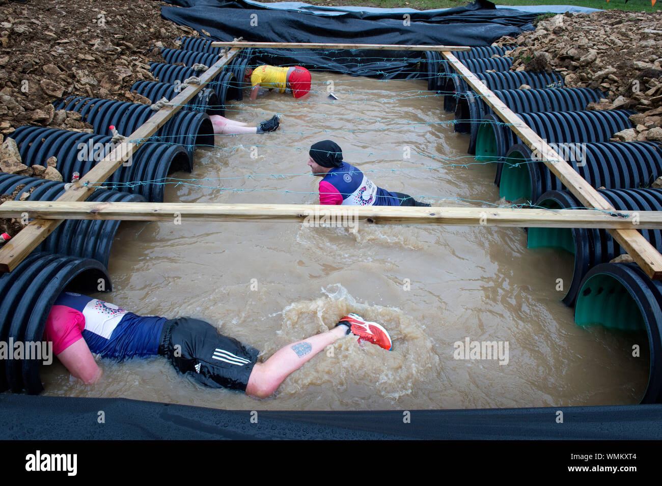 I concorrenti di negoziare la "Kiss di fango' ostacolo al duro Mudder endurance evento nel Parco di Badminton, GLOUCESTERSHIRE REGNO UNITO Foto Stock