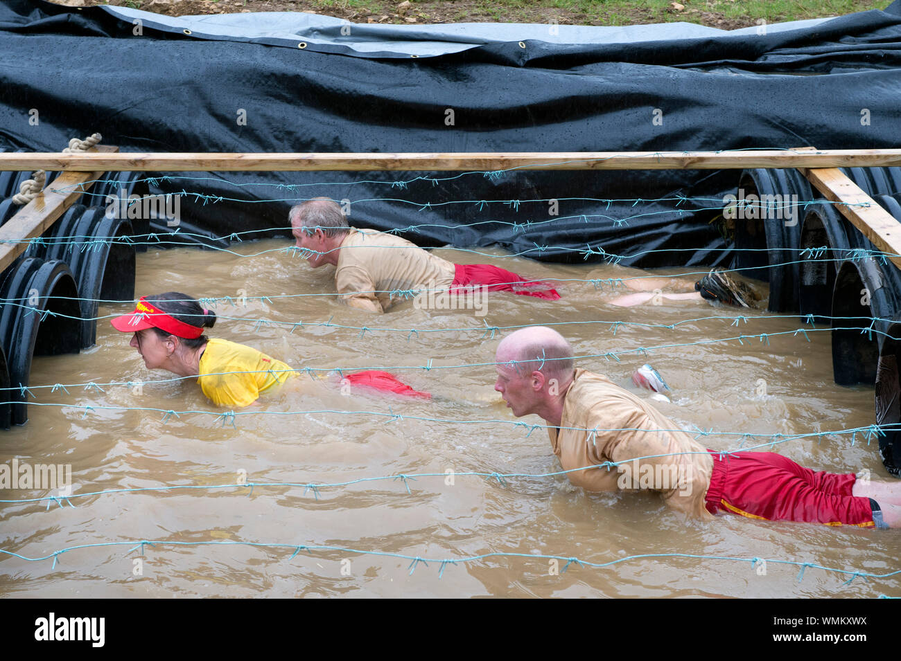 I concorrenti di negoziare la "Kiss di fango' ostacolo al duro Mudder endurance evento nel Parco di Badminton, GLOUCESTERSHIRE REGNO UNITO Foto Stock