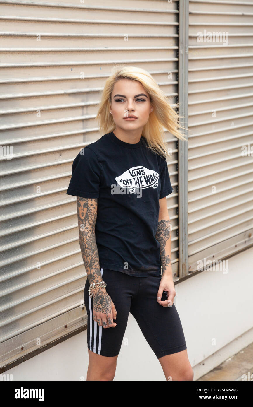 Una giovane donna bionda con tatuaggi indossare pantaloncini ciclo come una moda, Scozia. Foto Stock