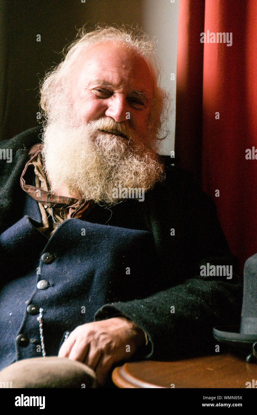 Un gentiluomo Vittoriano con un lungo occupato barba grigia, rilassante in una sala di un hotel in via principale al Sovereign Hill open-air-museum nel sobborgo Foto Stock