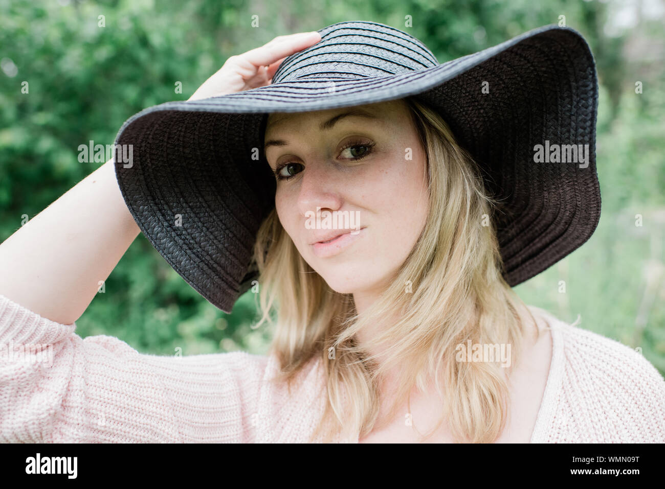 Ritratto di una donna in piedi guardando la telecamera sorridendo con un cappello Foto Stock