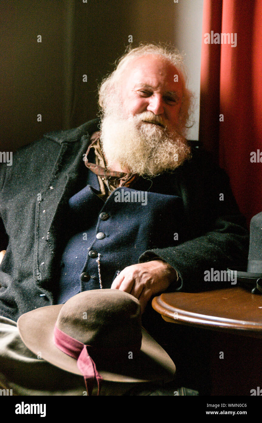 Un gentiluomo Vittoriano con un lungo occupato barba grigia, rilassante in una sala di un hotel in via principale al Sovereign Hill open-air-museum nel sobborgo Foto Stock
