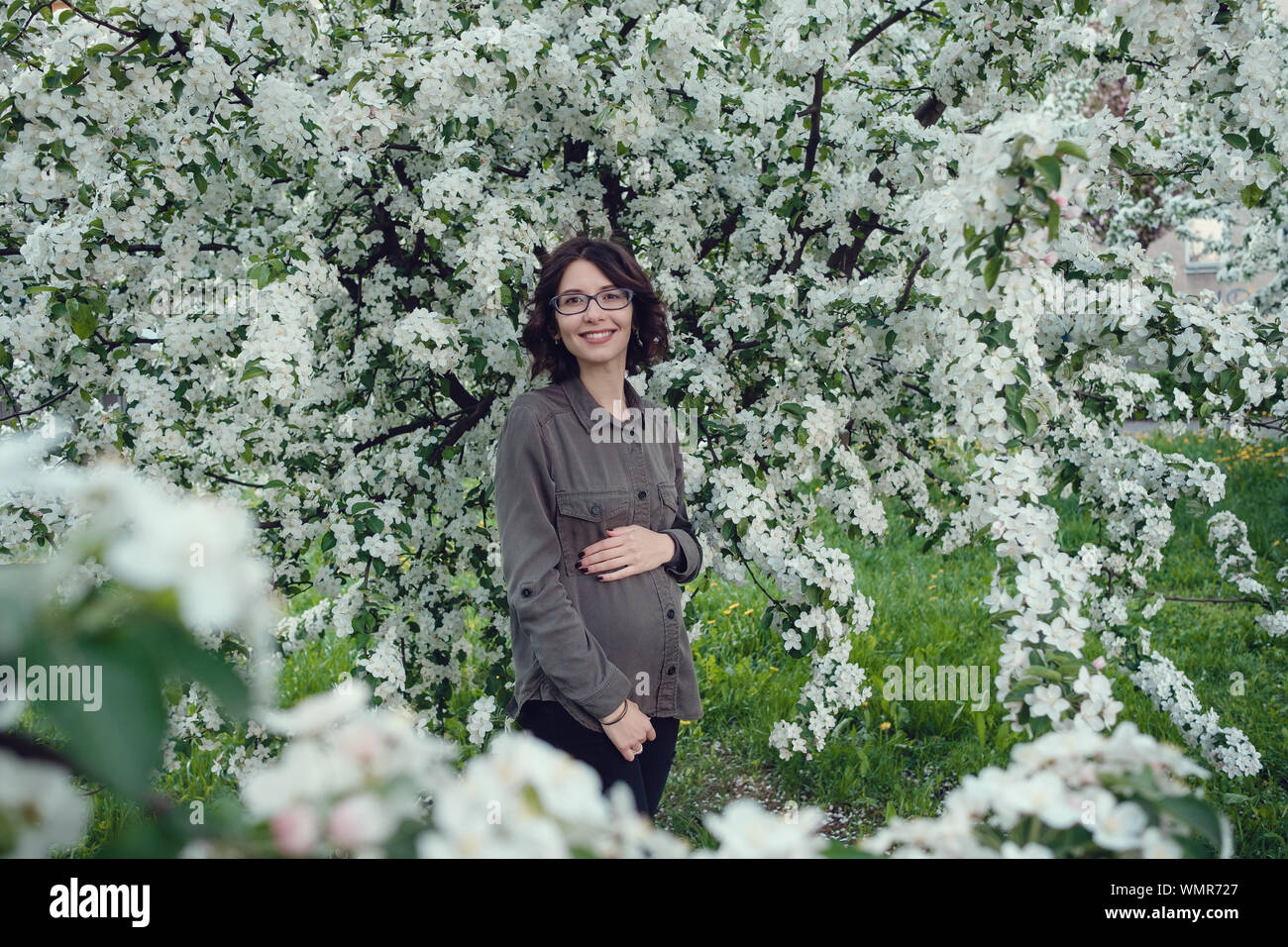 Una giovane donna incinta in un meleto nel cuore di Varsavia. Relax in primavera in Polonia Foto Stock