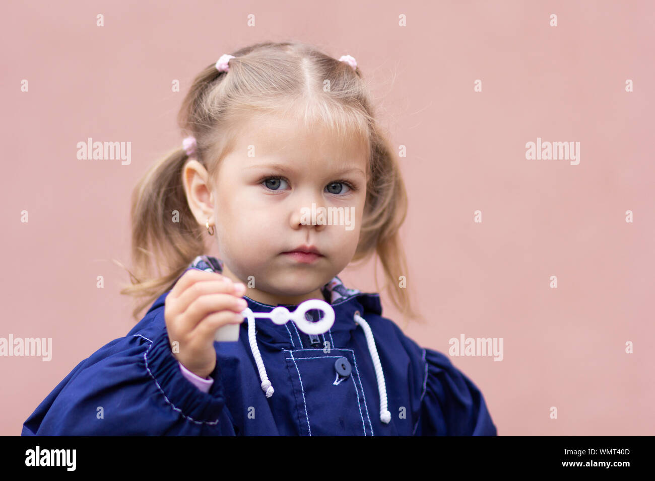 Ritratto della bambina soffiando bolle di sapone su sfondo rosa Foto Stock