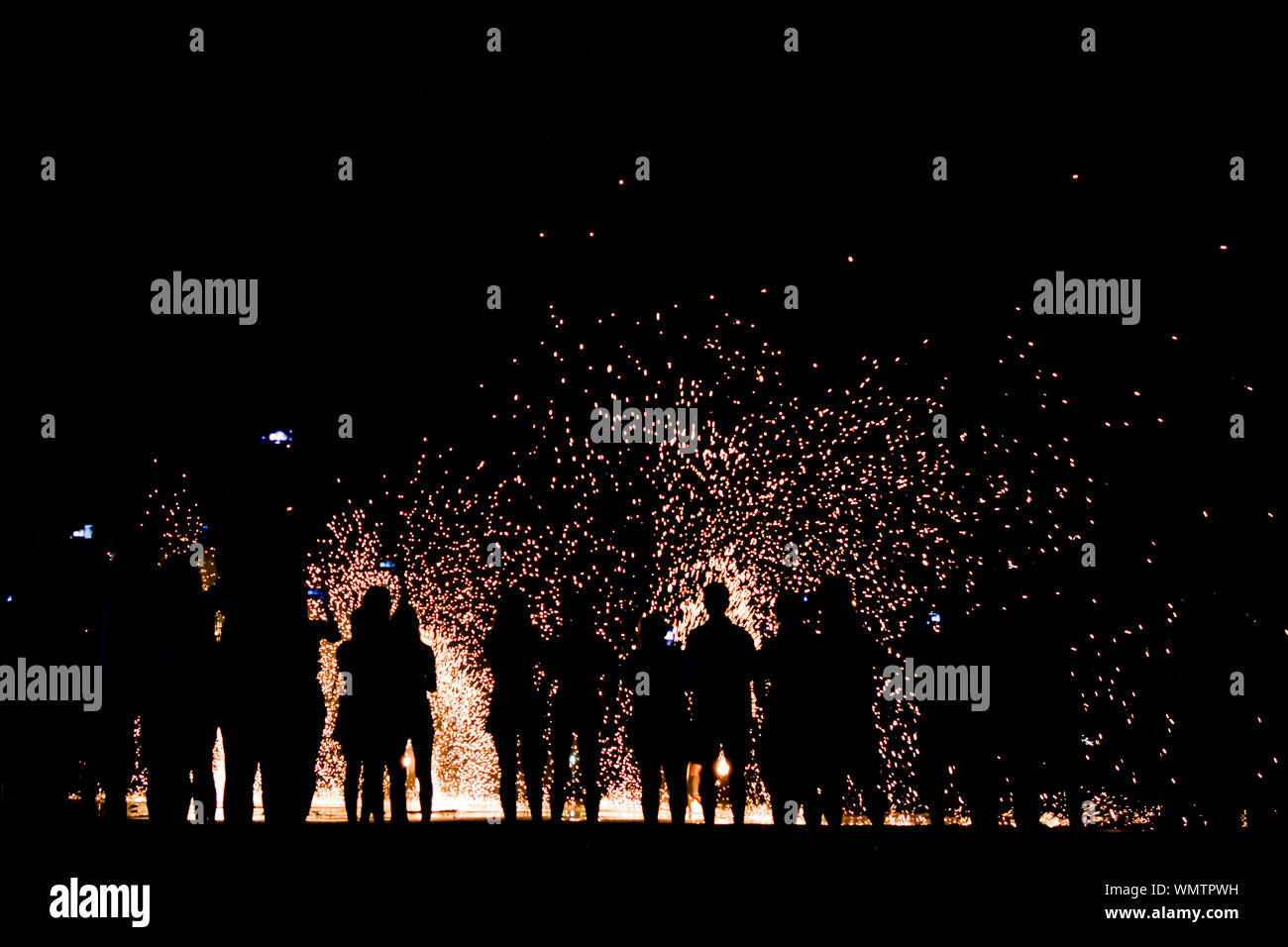 La folla in piedi contro di fuochi d'artificio di notte Foto Stock