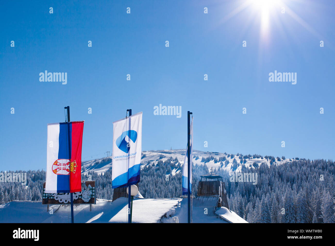 Il serbo e ski resort bandiere sulla montagna innevata con alberi di sfondo e sun in un angolo. Posto per il testo Foto Stock