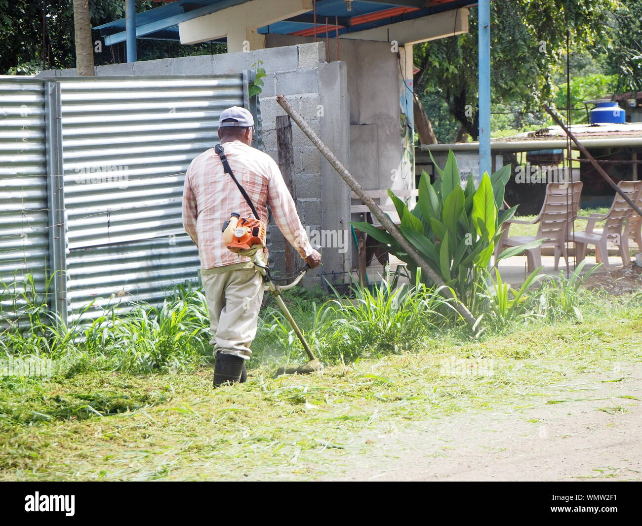 tagliabasette da giardiniere o cespugliatore da lavoro che tagliano l'erba lungo il lato dell'imboscata stradale Foto Stock