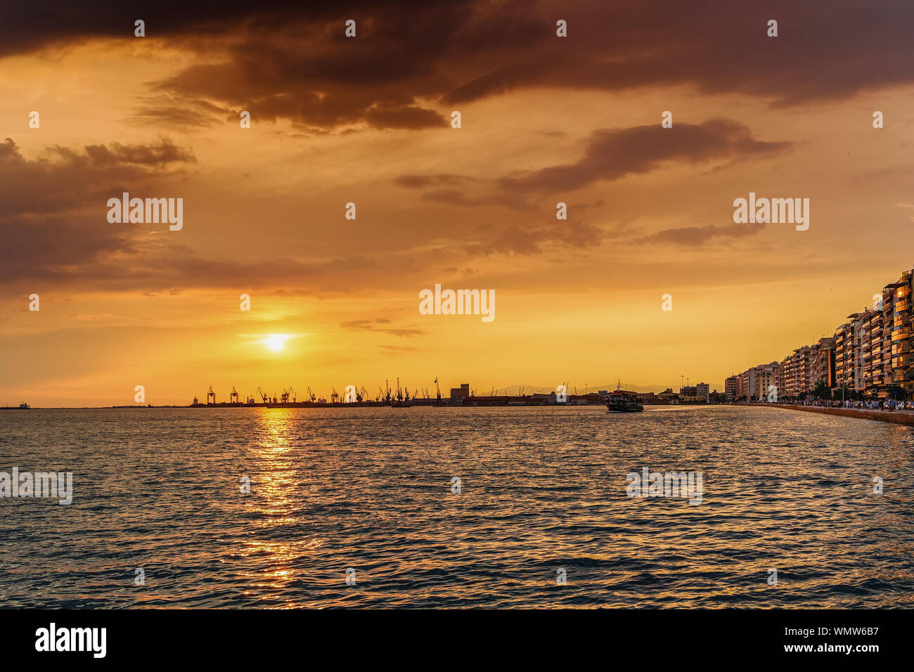 Salonicco Grecia golden ora città porta panorama al tramonto con nave turistica la vela. Arancione tramonto sopra porto e città edifici con waterfront folla. Foto Stock
