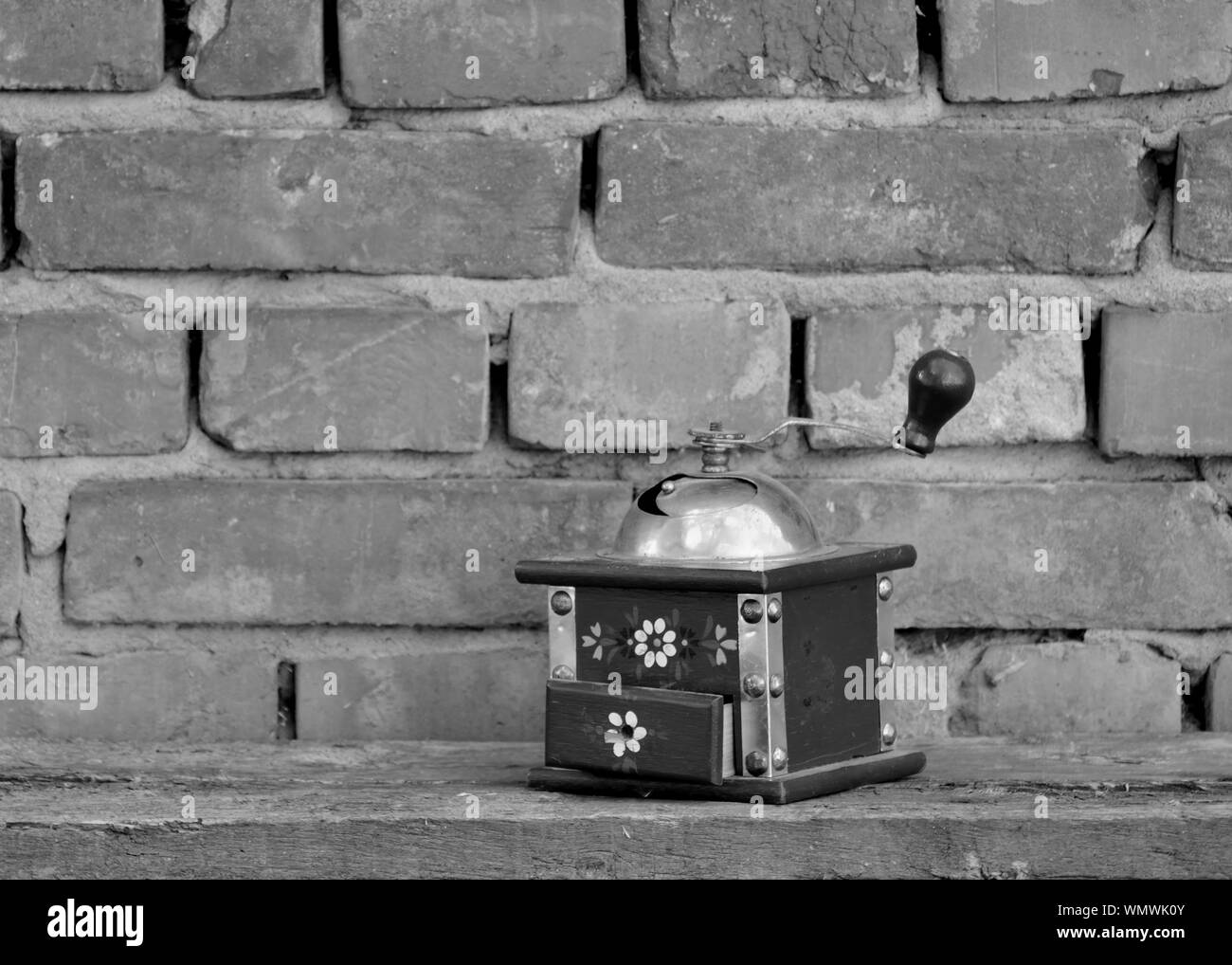 Vintage macinino da caffè su una tavola di legno con il vecchio muro di mattoni in background Foto Stock