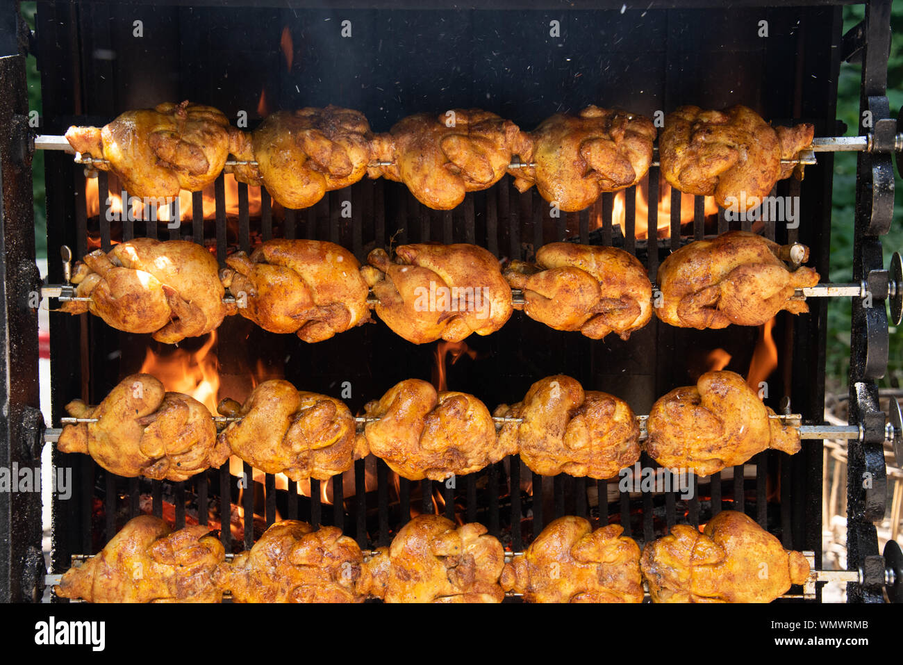 Sullo sfondo di un pollo alla griglia al mercato alimentare a un cibo carrello con bella gustoso pollo davanti a un caminetto a gas Foto Stock