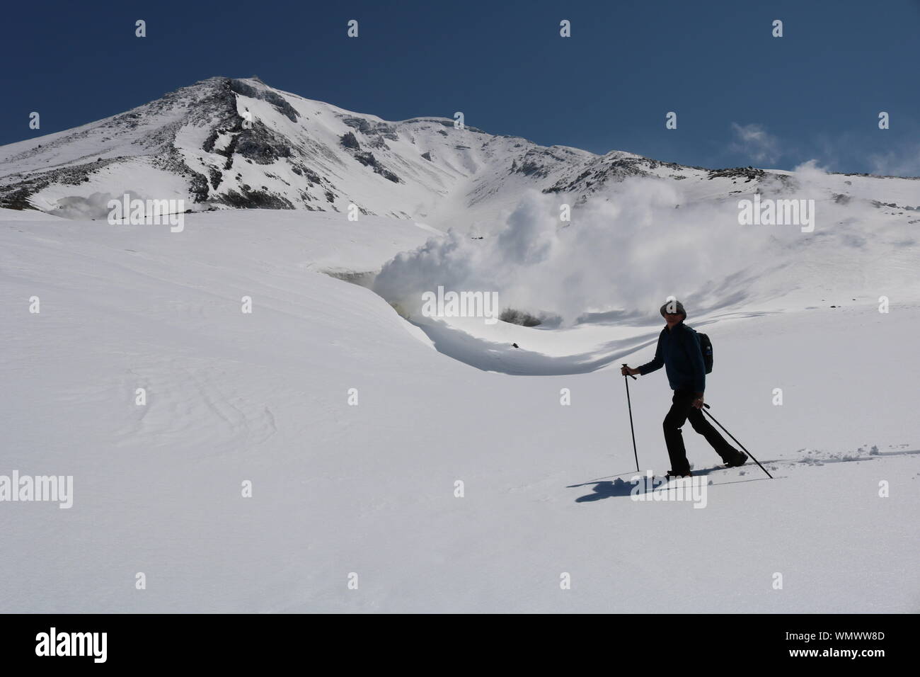 Uomo racchette da neve di fronte al vulcano attivo fumante Foto Stock