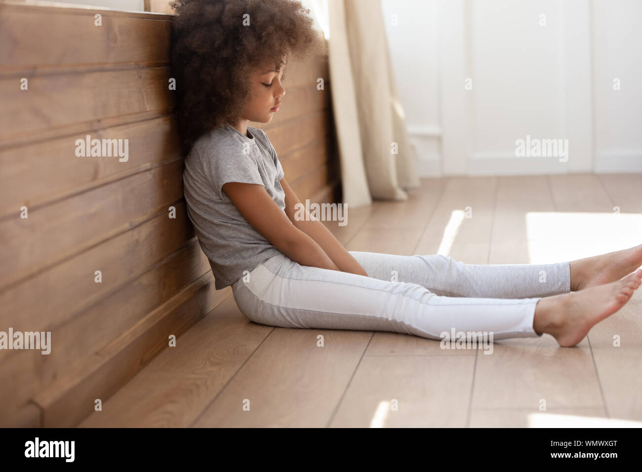 Sconvolto nero capretto carina ragazza seduta da sola sul pavimento. Foto Stock