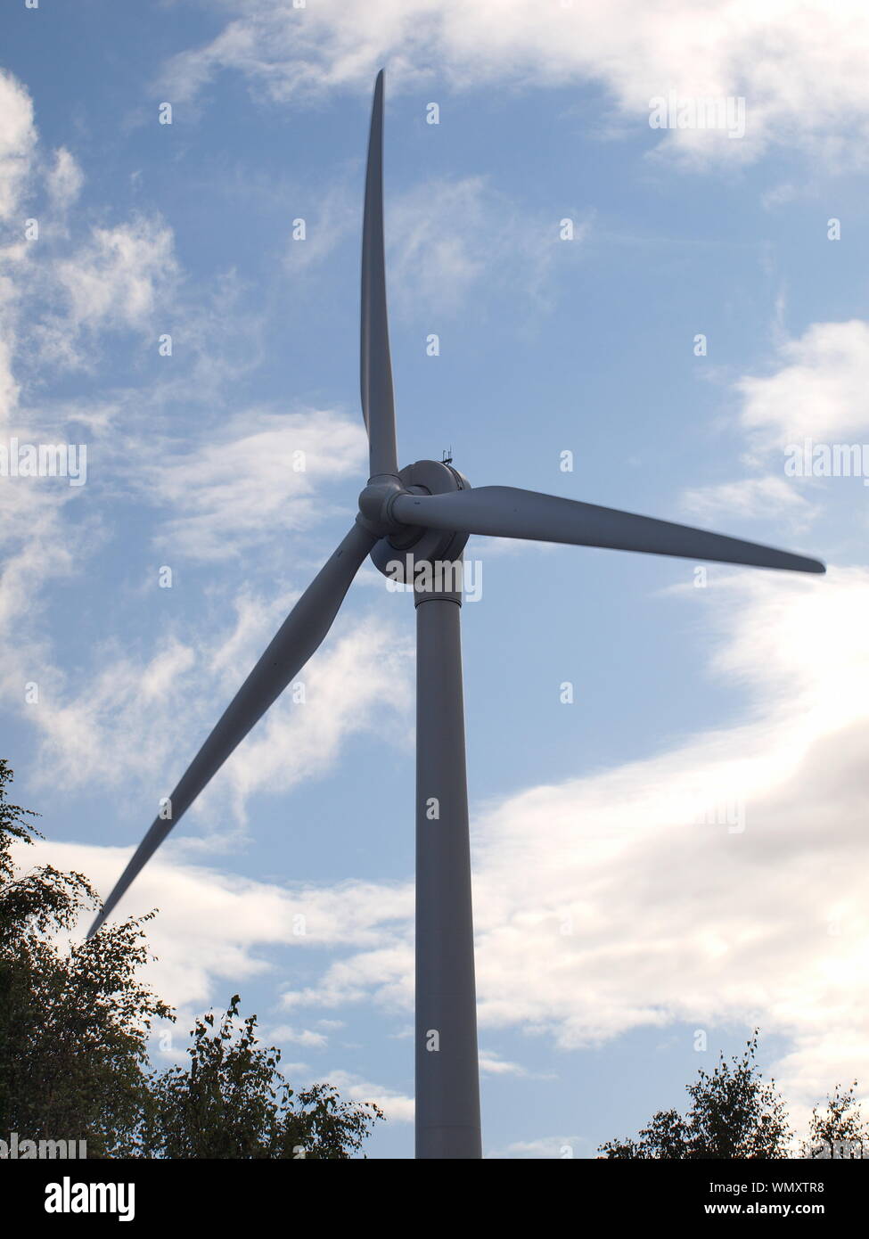 Turbina eolica/generatore girato in condizioni di luce diurna con cielo azzurro sfondo con poche nuvole Foto Stock