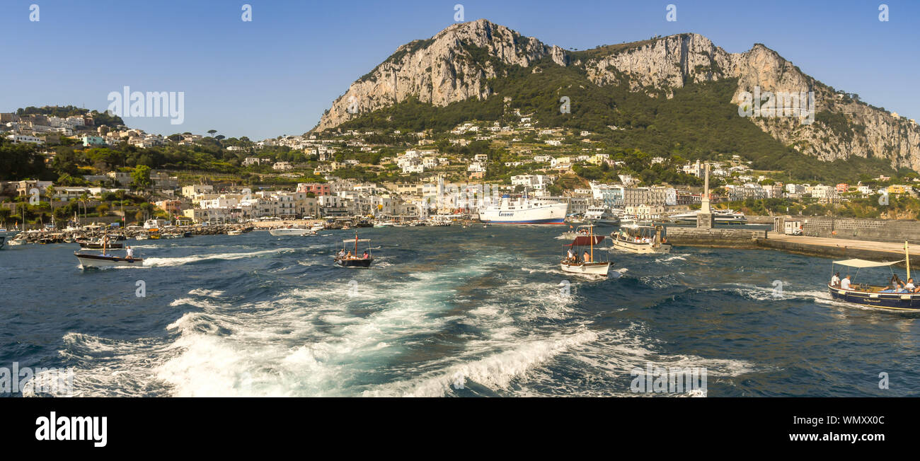 Isola di Capri - Agosto 2019: vista panoramica del porto dell'isola di Capri. Un ferrry è ormeggiata nel porto e piccole imbarcazioni stanno lasciando. Foto Stock