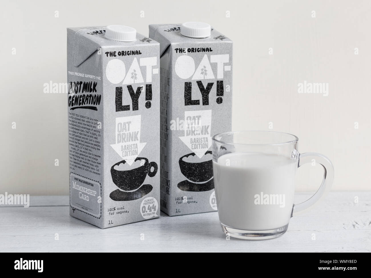London / UK - 2 Settembre 2019 - Oatly cartoni di latte e un bicchiere di latte oatly su un tavolo di legno. Oatly è un caseificio vegano libera alternativa di latte Foto Stock