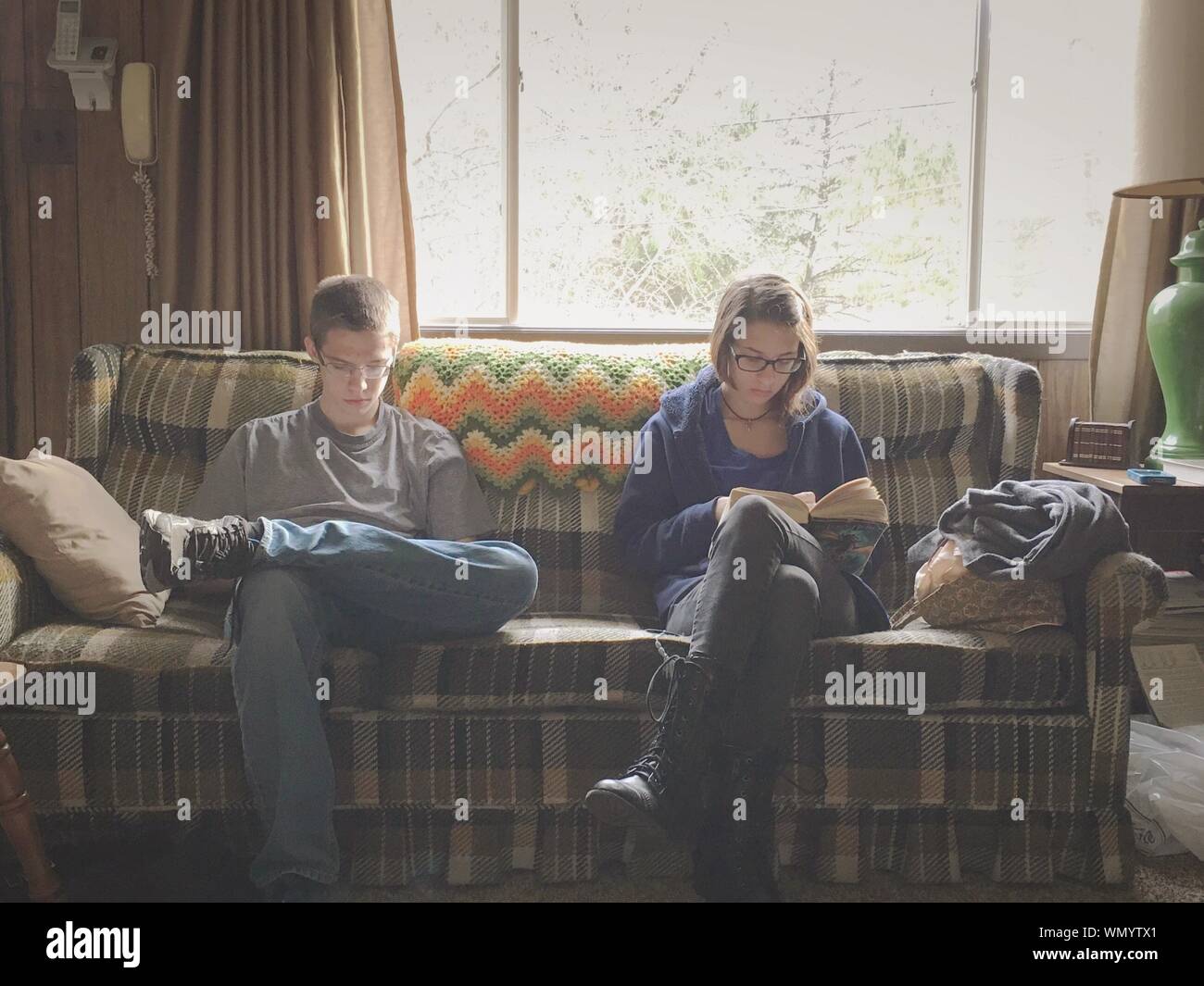 Due giovani adulti seduti sul divano di casa Foto Stock