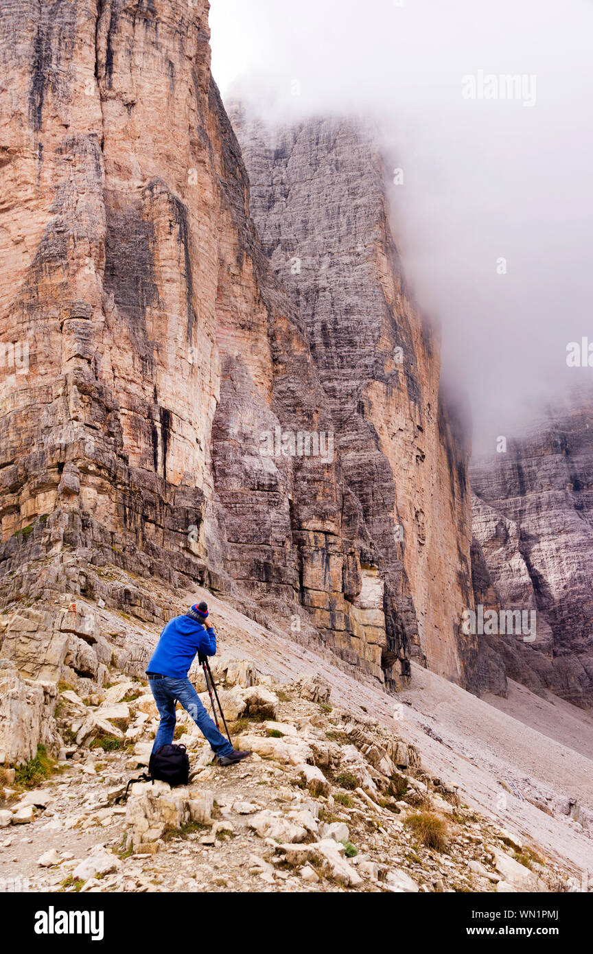 Vista posteriore dell'uomo a fotografare le Tre Cime di Lavaredo a Dolomiti durante la nebbia Meteo Foto Stock