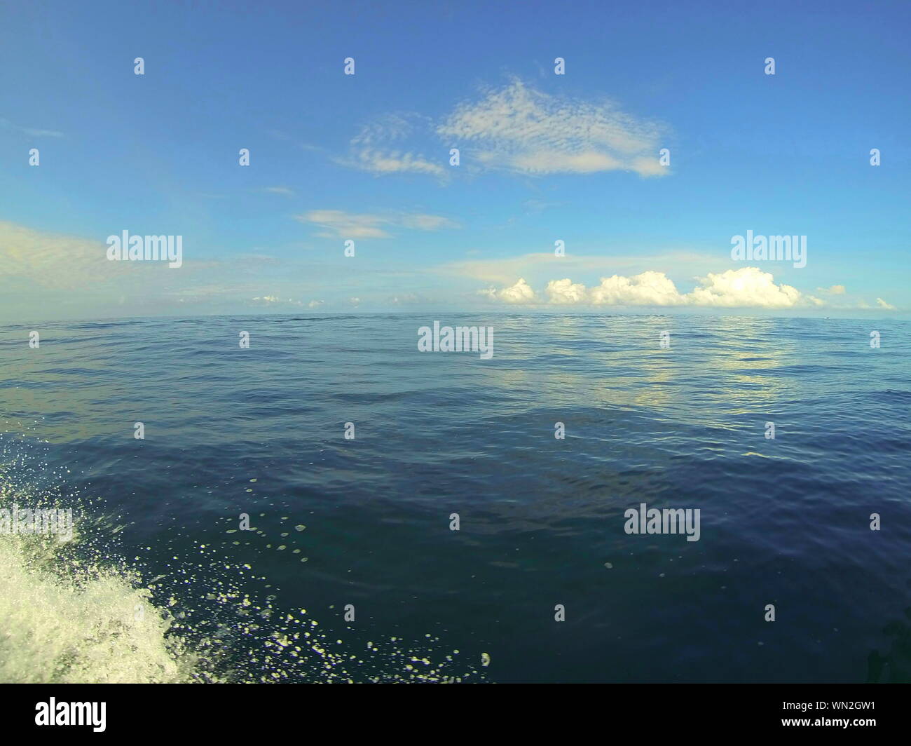 l'oceano calmo piatto. al mare in una barca con cielo blu e mare. onda di prua dalla barca Foto Stock