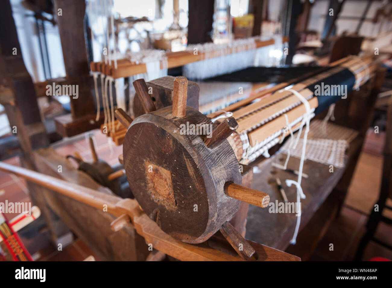 Primo piano delle merci di albero su un vecchio legno macchina di tessitura in vista prospettica. Foto Stock
