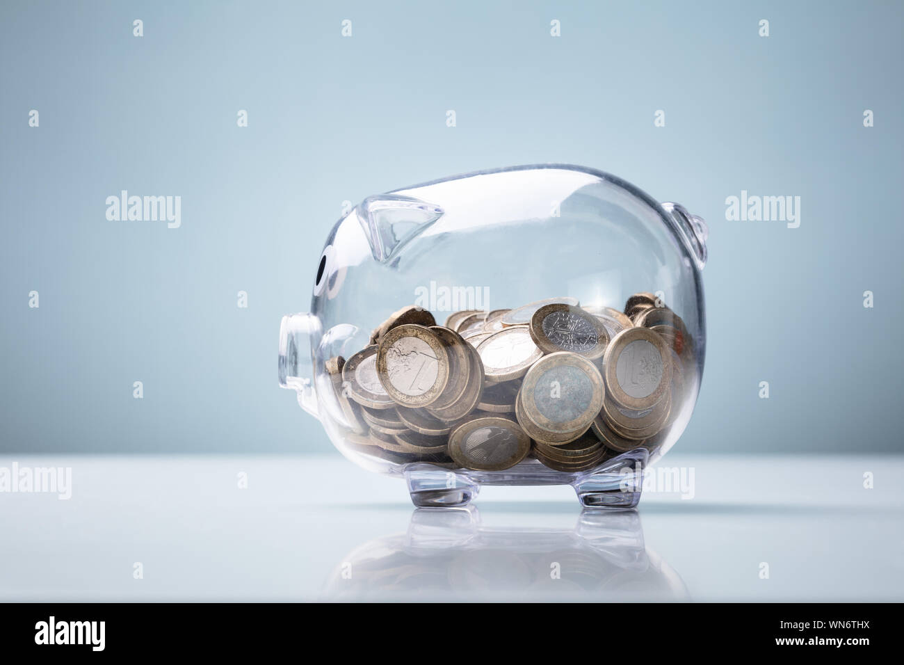 Trasparente Salvadanaio con piena di monete sul banco in bianco su sfondo  blu Foto stock - Alamy