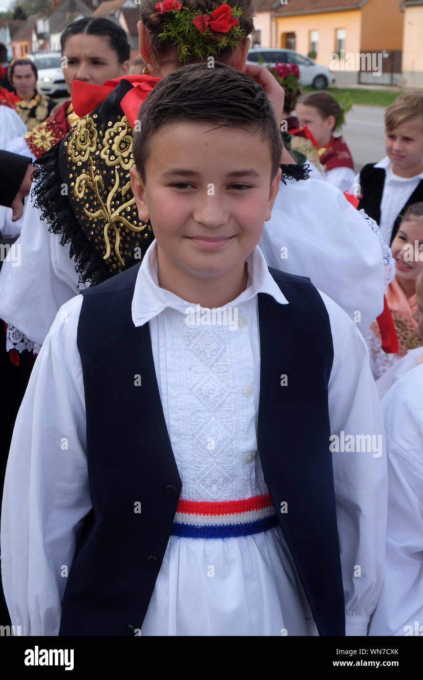 Ragazzo vestito in costumi folcloristici andare in chiesa durante la Santa Messa il giorno del Ringraziamento in Stitar, Croazia Foto Stock