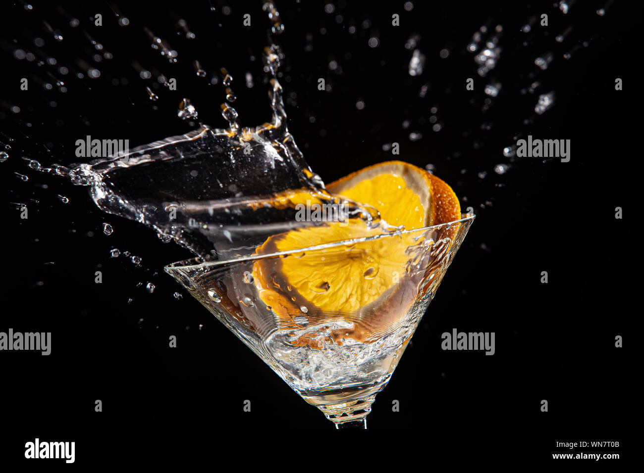 Vetro con arancia e ghiaccio con spruzzi di acqua Foto Stock