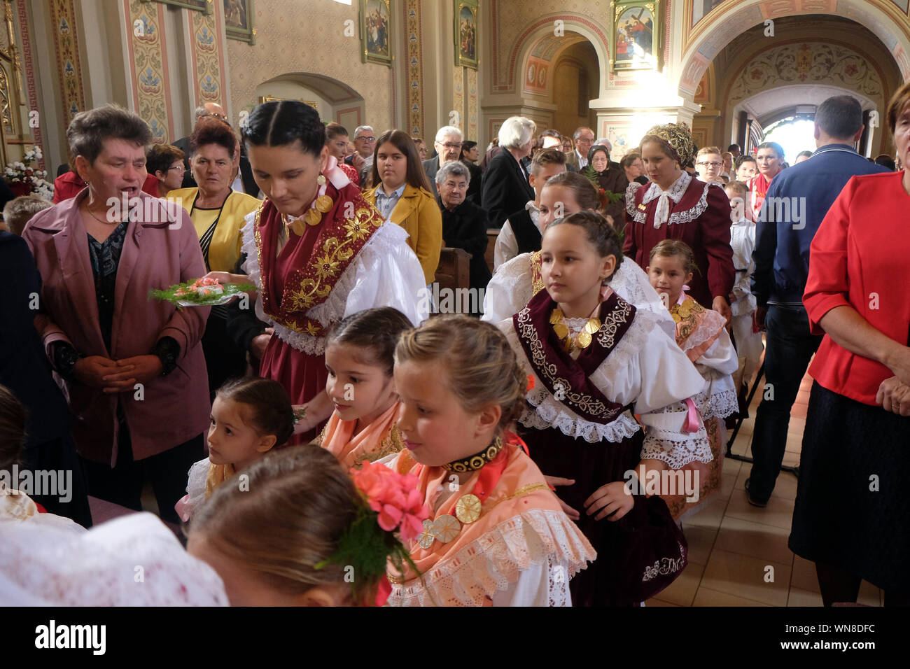 La gente vestita in regionali tradizionali costumi folk in chiesa durante la Santa Messa il giorno del Ringraziamento in Stitar, Croazia Foto Stock