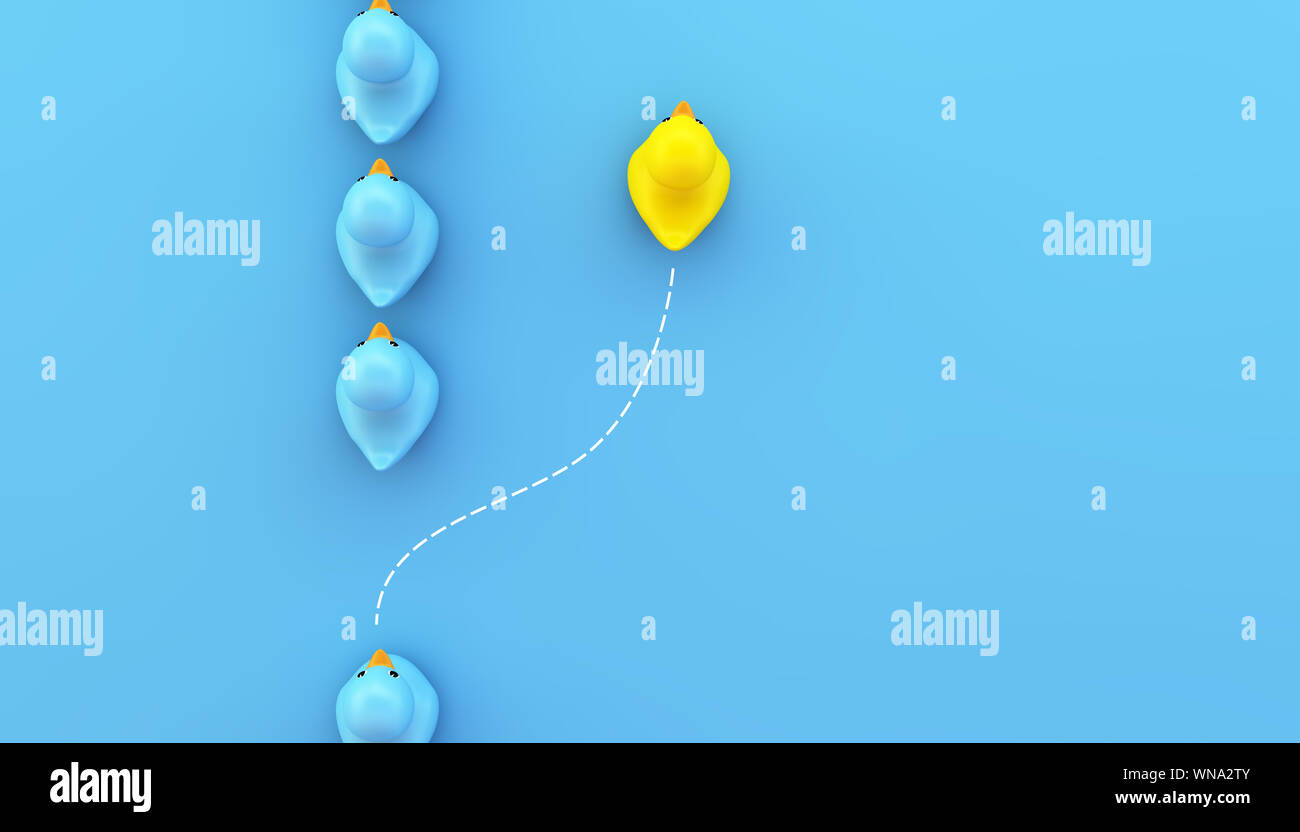 Gruppo di gomma blu anatre in una direzione e una gialla rivolta in modo diverso su sfondo blu. Foto Stock
