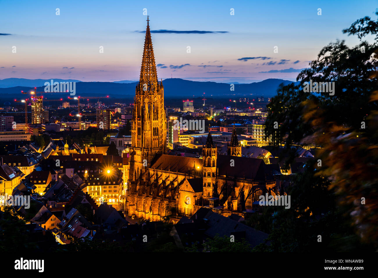 Germania, paesaggio e sullo skyline di Freiburg im Breisgau con landmark minster o chiamato muenster chiesa nella magica atmosfera del crepuscolo dopo il tramonto a du Foto Stock