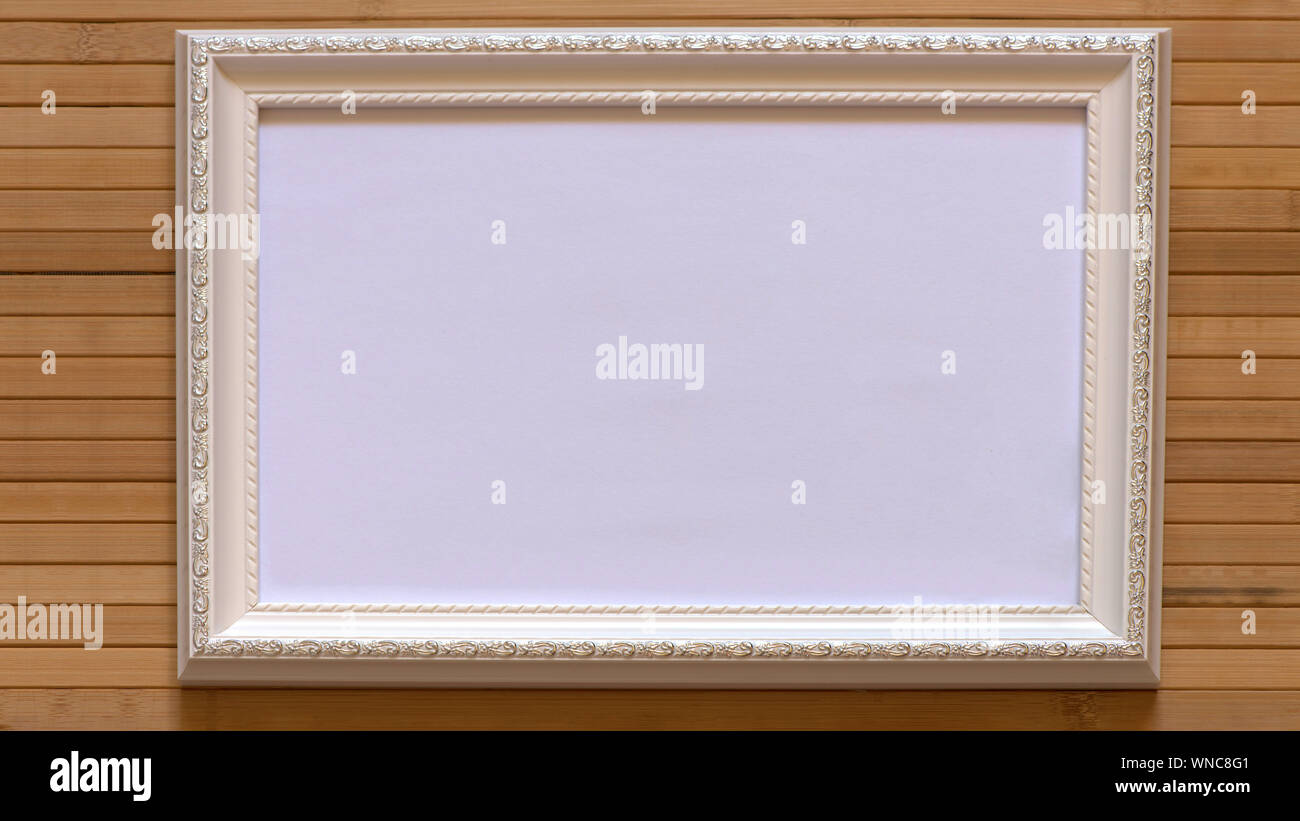 Bianco con telaio vuoto tela bianca su di bamboo naturale parete. Immagine orizzontale 16:9 con disegno utile per il vostro ingresso all'interno del testo, immagine etc. Foto Stock