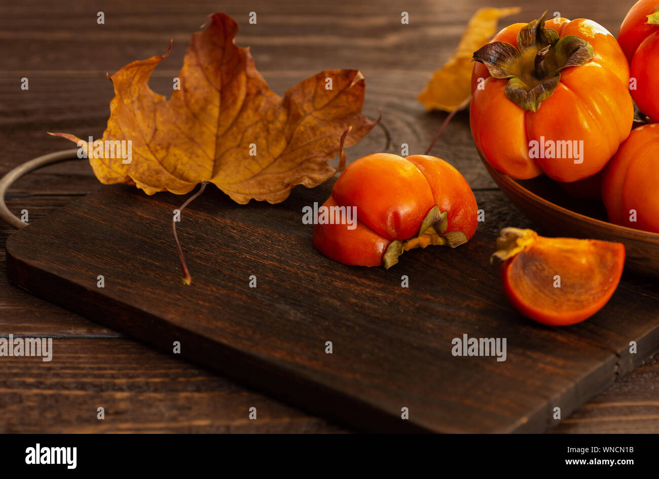 Persimmons maturi su uno sfondo di legno. Persimmon varietà Fuyu. Close-up. Foto Stock