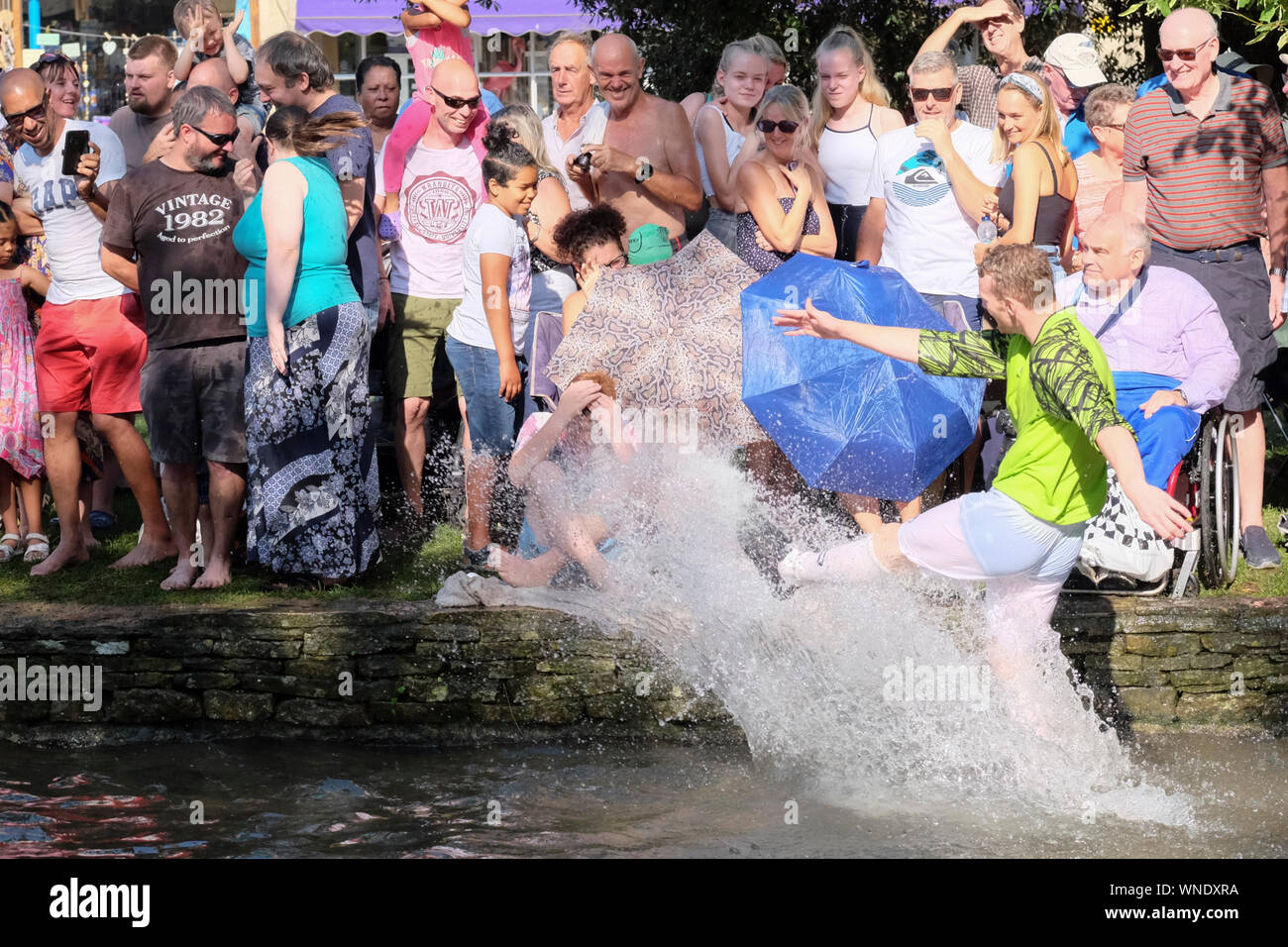 A ferragosto festeggiamenti a Bourton-sul-l'acqua GLOUCESTERSHIRE REGNO UNITO. Le tradizionali calcio nel fiume corrispondono. Gli schizzi della folla. Foto Stock