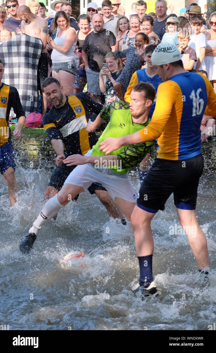 A ferragosto festeggiamenti a Bourton-sul-l'acqua GLOUCESTERSHIRE REGNO UNITO. Le tradizionali calcio nel fiume corrispondono. Foto Stock