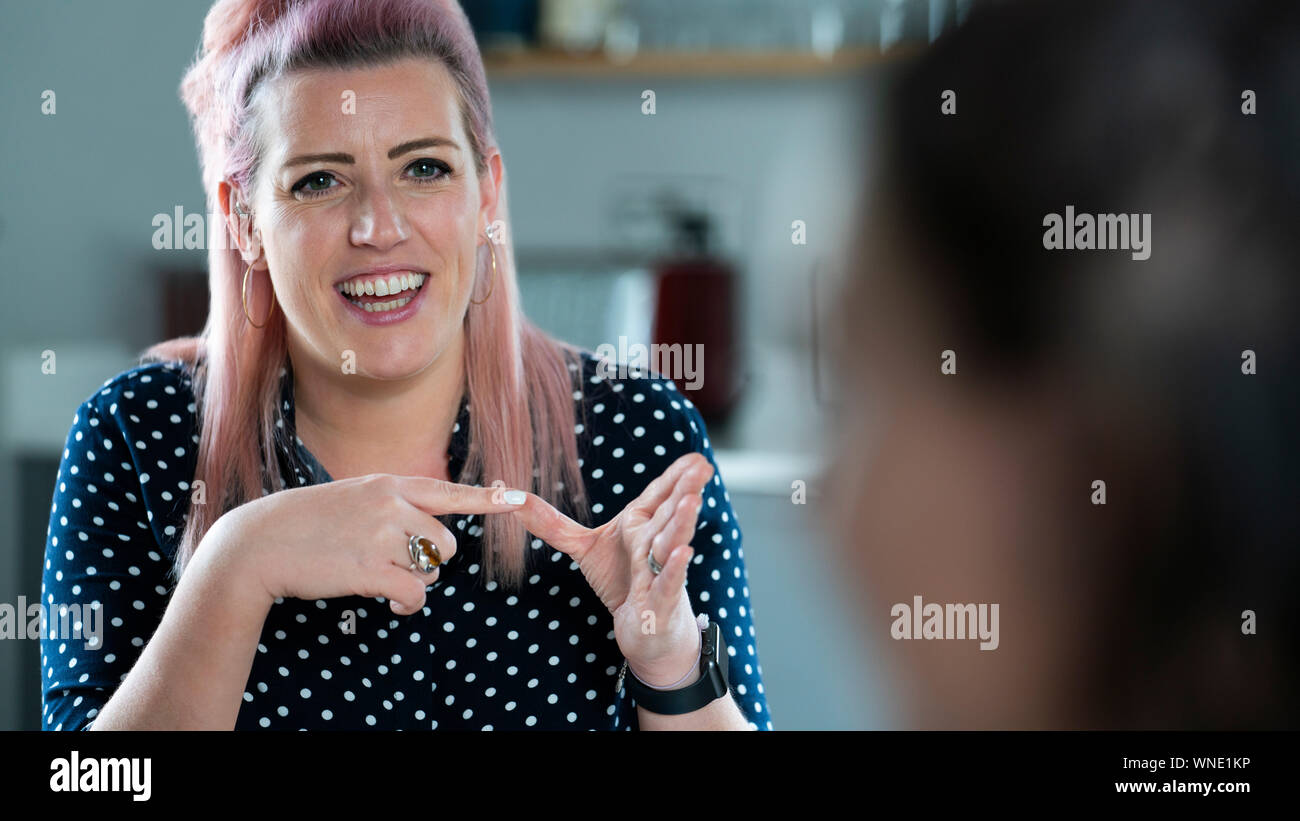 Due donne aventi la conversazione a casa utilizzando il linguaggio dei segni Foto Stock