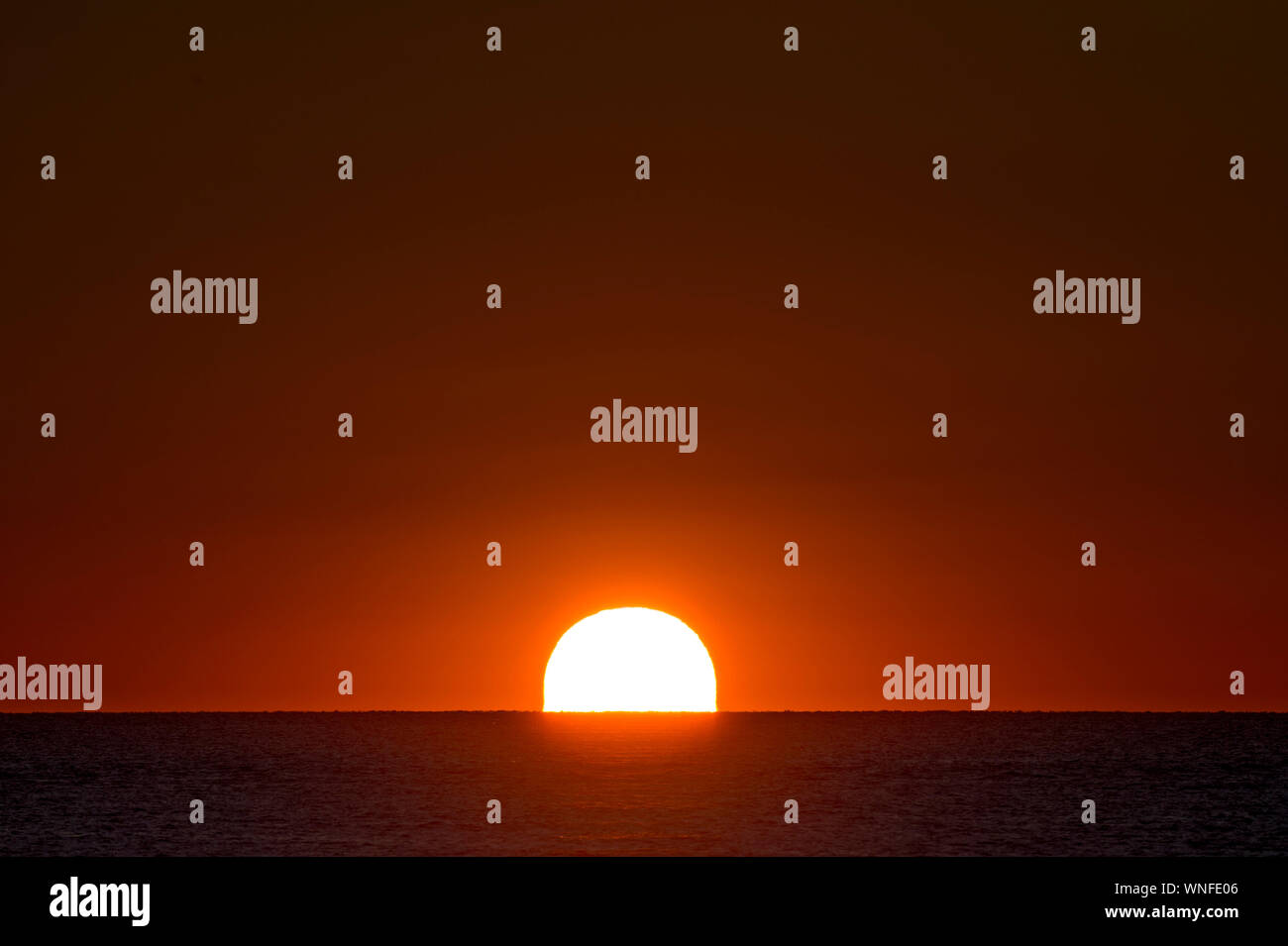 Grande il sorgere del sole sopra l'oceano con completamente arancione chiaro e rosso del cielo. Foto Stock