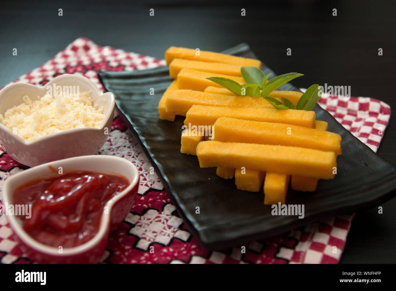 Polenta patatine con salsa di pomodoro e formaggio. Antipasti italiani. Fritti bastoncini di mais. Foto Stock