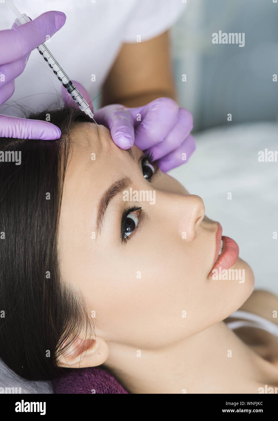 Donna asiatica la ricezione di iniezione nel mimare ruga sul fronte . Procedura di eliminazione di rughe Foto Stock